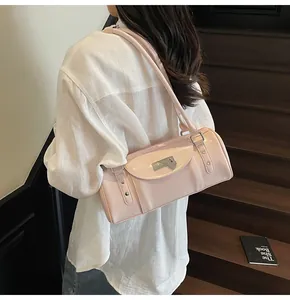Détail d'un sac à bandoulière cylindrique rose avec fermoir en métal et pendentif coeur
