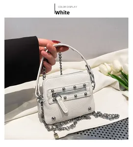 Close-up of small white leather waist bag with silver rivets and heavy metal chain