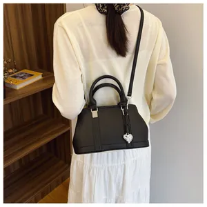 Detail of black lychee grain leather bag with round handles and silver heart charm