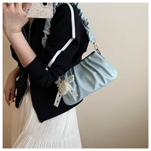 Detail of light blue ruched cloud bag featuring a pearl bow pendant and ruffled handle