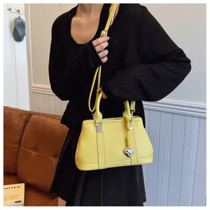 Detail of yellow lychee pattern leather handbag featuring a gold heart charm and strap