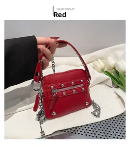 Detail of red pebbled leather mini bag with silver rivets and metal chain strap