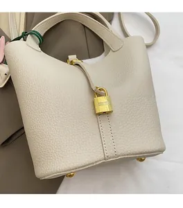 Close-up of cream leather bucket bag showing litchi texture and golden padlock detail