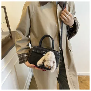 Detail of black mini handbag with plush bunny charm on a khaki trench coat