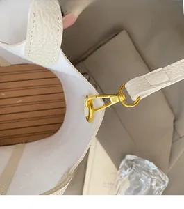 Detailed macro view of high-quality gold hardware and striped lining on white bucket bag