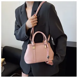 Detailed view of pink lychee leather crossbody bag with heart pendant and silver hardware