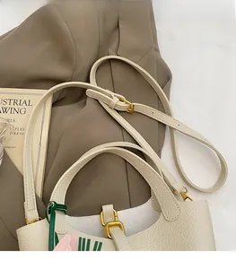 Detail of cream crossbody bucket bag featuring pink tulip patterns and adjustable strap