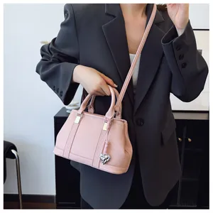 Detailed macro view of pink lychee grain leather handbag with silver heart pendant