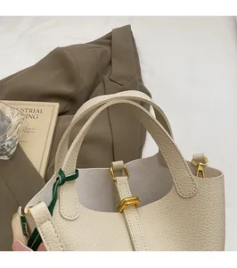 Detail of cream white leather bucket bag with gold hardware and colorful decorative charms