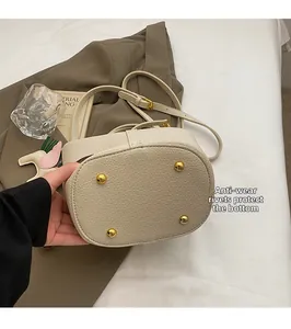 Close-up of golden metal rivets on the bottom of the beige pebbled leather bucket bag