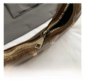 Close-up of matte bronze zipper on dark brown pebbled leather shoulder bag