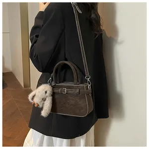Detail of dark brown faux suede bag featuring contrast stitching and a cute rabbit charm