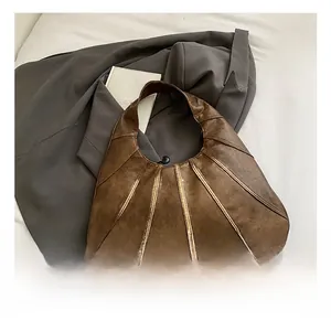 Detail of a brown vintage crescent bag with pleated stitching on grey blazer background