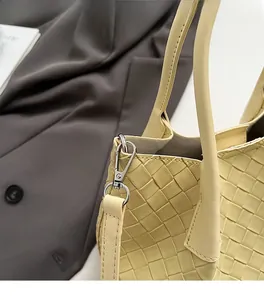 Détail du crochet en métal argenté et de la texture en cuir tressé du sac jaune
