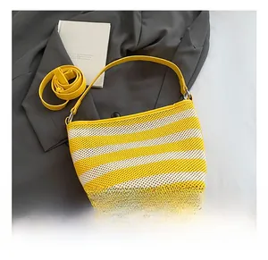 Macro detail of yellow striped woven tote bag featuring leather handles and strap