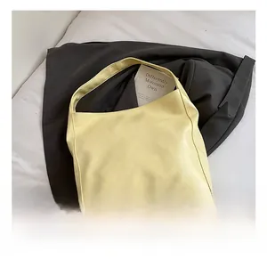 Detail view of large cream faux leather tote bag placed on a grey blazer for daily commute