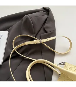 Détail du sac seau tressé beige avec bandoulière réglable et texture élégante raffinée