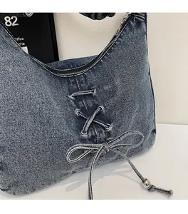 Détail du sac hobo en jean bleu avec laçage décoratif croisé et un nœud élégant