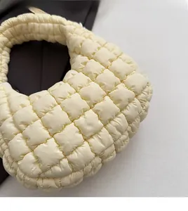 Detailed close-up of soft quilted texture and padded handle on beige cloud bag