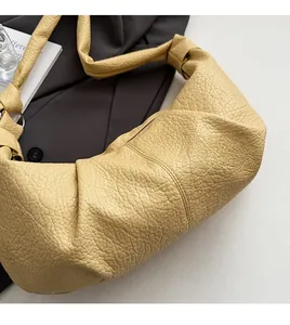 Close-up of yellow pleated hobo bag with textured lychee grain and knot detail