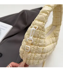 Detail of the durable shoulder strap hook on a creamy yellow quilted puffer cloud bag