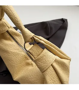 Detail of yellow lychee grain leather bag showing the silver ring and knotted handle