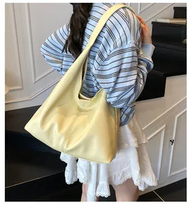Detailed side view of a large pale yellow lychee leather Hobo bag worn on the shoulder