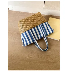 Close-up of contrast straw and blue-white striped canvas tote bag with side metal D-ring
