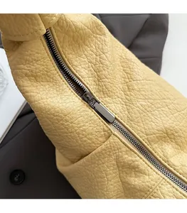 Detail of smooth metal zipper on yellow lychee grain leather crossbody bag