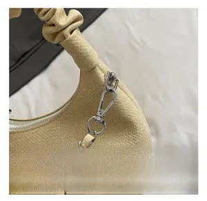 Macro shot of silver metal lobster clasp and textured gathered handle on a cream cloud bag