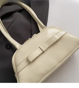 Detail of soft cream white bowling bag with glossy finish on a dark blazer background