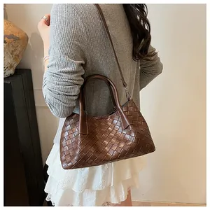Détail du sac à main en cuir tressé marron foncé avec bandoulière sur le modèle