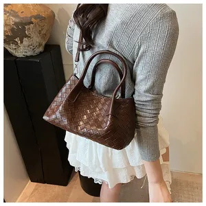 Détail d'un sac seau en cuir tressé marron foncé avec doubles poignées et clips en métal