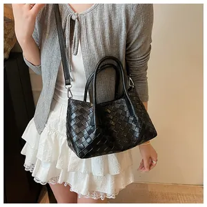 Détail d'un sac cabas en cuir tressé noir avec double poignée et une longue bandoulière