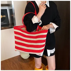 Vue détaillée du sac cabas en tricot rayé rouge et blanc avec anses en cuir rouge à l'épaule