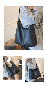 Detail view showing textured black lychee leather and stitching on the large hobo tote bag