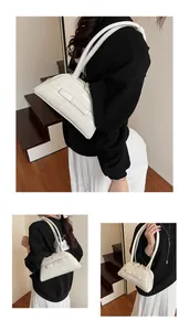 Detail view of a cream glossy leather baguette bag with bow accent and slim double straps