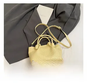 Detailed close-up of woven cream bucket bag with unique knot handle and adjustable strap
