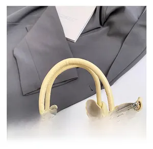 Detail of woven cream leather bucket bag handle with metallic D-ring and hook
