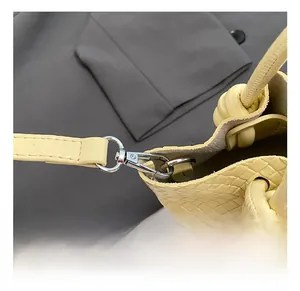 Macro shot of silver rotating hook and woven leather detail on creamy yellow bucket bag
