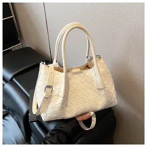 Détail du sac cabas tressé crème montrant la texture du cuir et la bandoulière