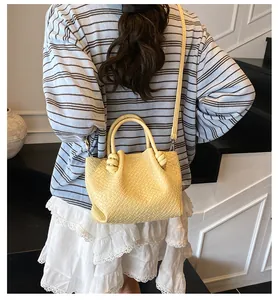 Detail of yellow woven texture on stylish bucket bag worn by model with striped top