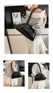 Detail of a shiny black faux leather shoulder bag featuring minimalist retro design