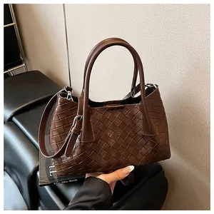 Détail du sac seau en cuir tressé marron foncé avec poignée et bandoulière réglable