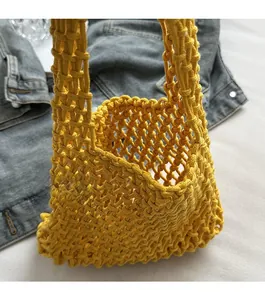 Detail of yellow hollow knit tote bag showing intricate mesh texture and open design