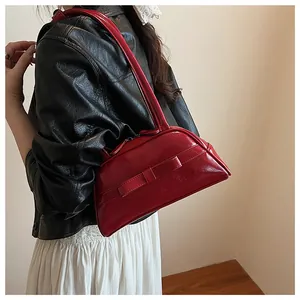 Red bow handbag style with glossy finish shown on model with chic outfit