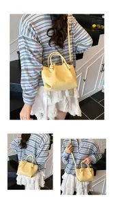 Detail of yellow woven bucket bag featuring knotted top handles and crossbody strap