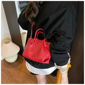 Detail of red woven bucket bag with smooth top handle and slim shoulder strap