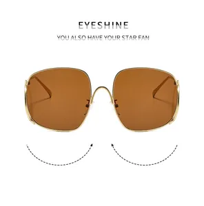 Détail de lunettes de soleil carrées surdimensionnées en métal doré et verres marrons