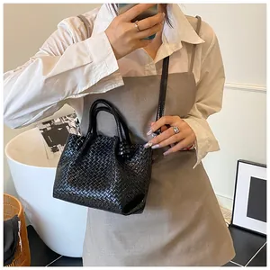 Detail of black woven bucket bag showing intricate checkerboard leather texture and handle